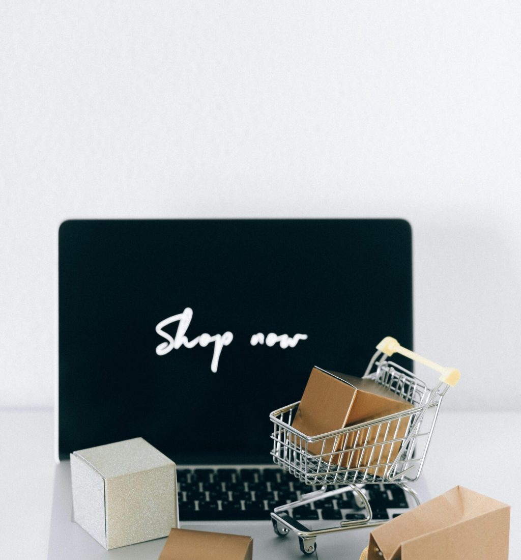 Minimalist online shopping setup with laptop, cart, and packages symbolizing e-commerce.
